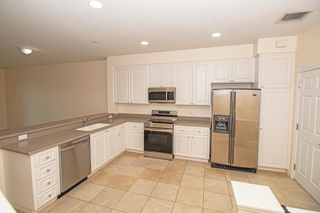 kitchen with light tile patterned flooring, appliances with stainless steel finishes, white cabinetry, and sink