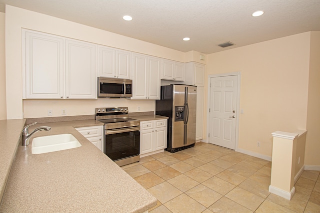 kitchen with light tile patterned floors, white cabinetry, sink, and appliances with stainless steel finishes