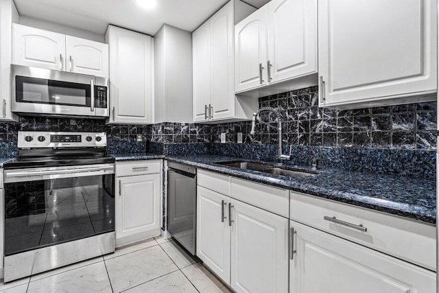 kitchen with sink, white cabinetry, appliances with stainless steel finishes, dark stone countertops, and decorative backsplash