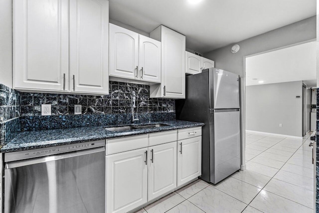 kitchen featuring sink, white cabinetry, appliances with stainless steel finishes, dark stone counters, and decorative backsplash