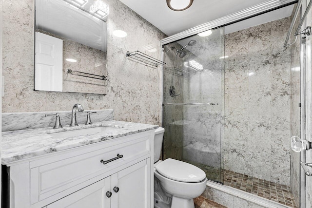 bathroom with vanity, a shower with door, and toilet