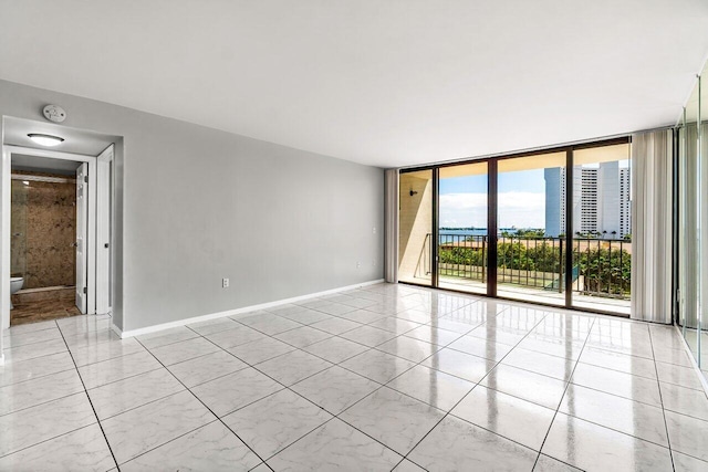 unfurnished room with a wall of windows and light tile patterned floors