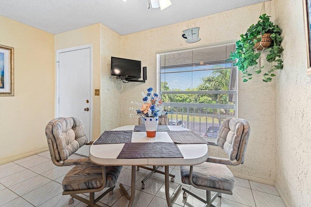 tiled dining space with a textured ceiling and ceiling fan