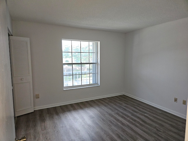 unfurnished room featuring a textured ceiling and dark hardwood / wood-style floors