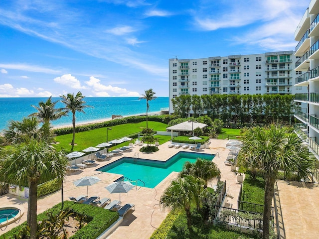 view of swimming pool with a water view, a beach view, a patio area, and a yard