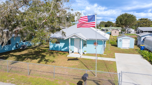 view of front of property featuring a front lawn and a storage shed