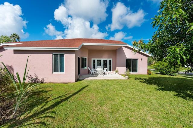 rear view of property featuring a lawn and a patio