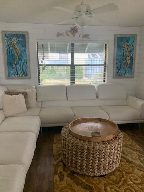 living room featuring ceiling fan and dark wood-type flooring