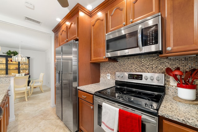 kitchen with light tile patterned floors, ornamental molding, backsplash, stainless steel appliances, and light stone countertops