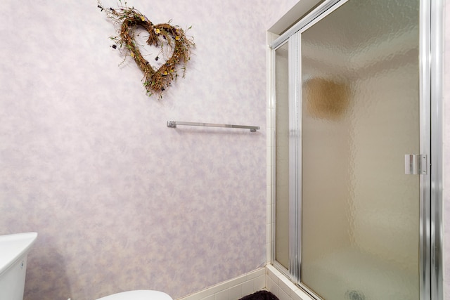 bathroom featuring toilet and a shower with shower door