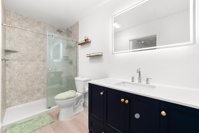 bathroom with hardwood / wood-style flooring, an enclosed shower, vanity, and toilet