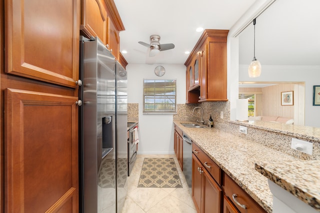 kitchen featuring pendant lighting, sink, light stone countertops, backsplash, and appliances with stainless steel finishes