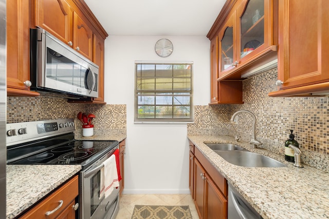 kitchen featuring decorative backsplash, light stone countertops, light tile patterned flooring, and appliances with stainless steel finishes