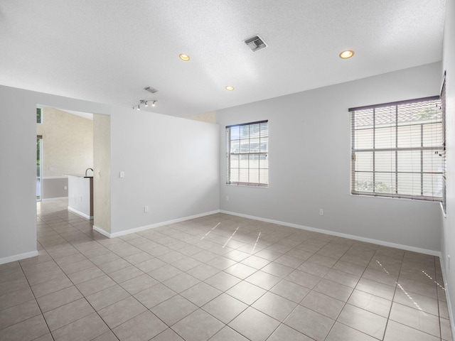 spare room featuring a textured ceiling and light tile patterned flooring