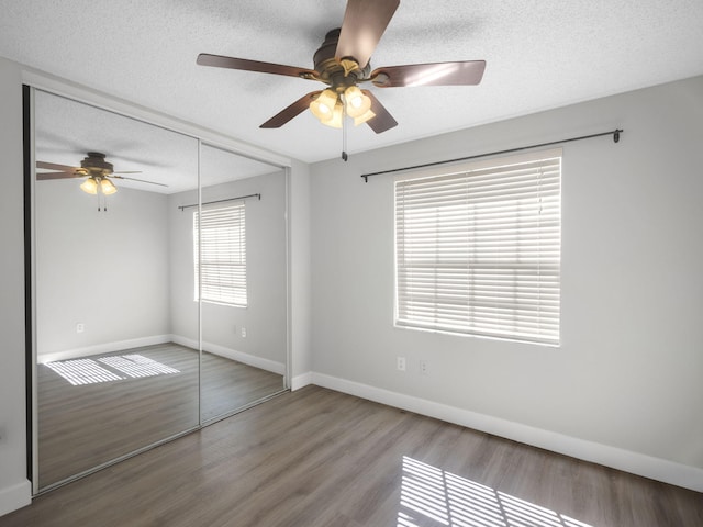 unfurnished bedroom with hardwood / wood-style flooring, ceiling fan, a textured ceiling, and a closet