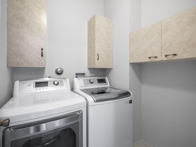 clothes washing area with cabinets and washing machine and clothes dryer