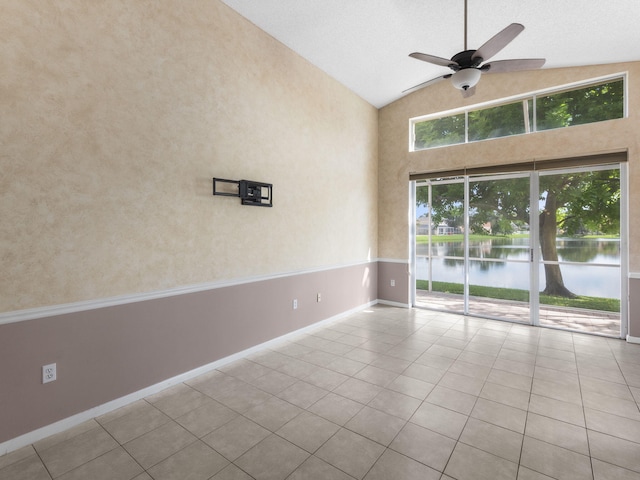 tiled empty room featuring high vaulted ceiling, a water view, and ceiling fan