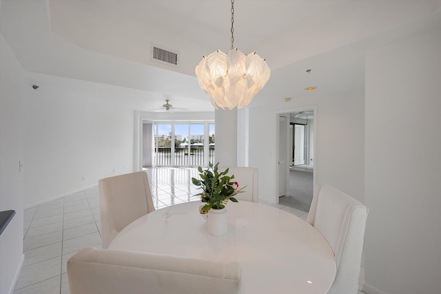 dining room with ceiling fan with notable chandelier, a water view, and light tile patterned floors