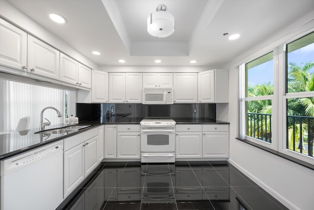 kitchen with dark tile patterned flooring, sink, white cabinets, white appliances, and a raised ceiling