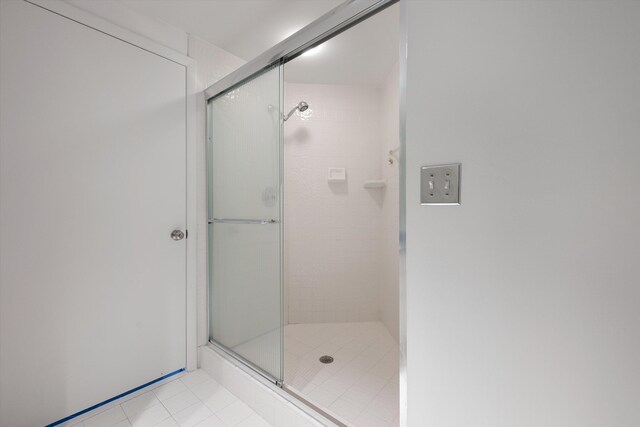 bathroom featuring tile patterned flooring, toilet, and an enclosed shower