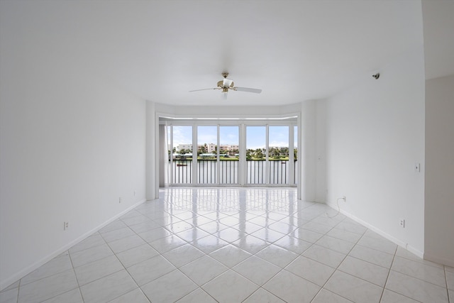 tiled empty room featuring a water view and ceiling fan