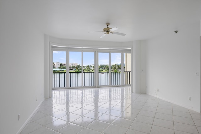 tiled empty room with ceiling fan and a water view