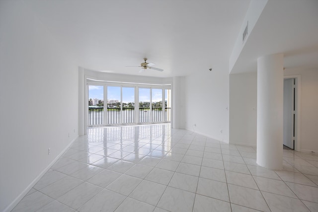 tiled spare room featuring a water view and ceiling fan