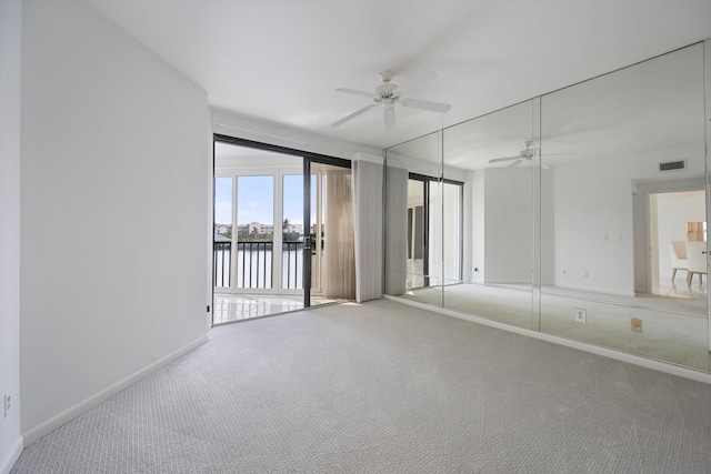 carpeted spare room featuring ceiling fan and a water view