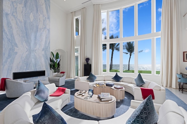 living room featuring a water view, ornamental molding, a wealth of natural light, and a high end fireplace