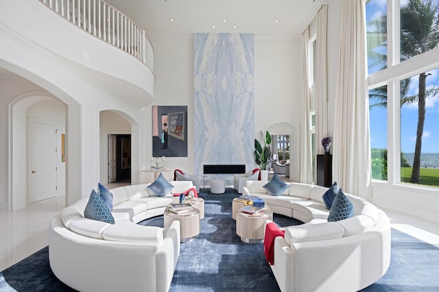 living room featuring ornamental molding, a high end fireplace, and a high ceiling