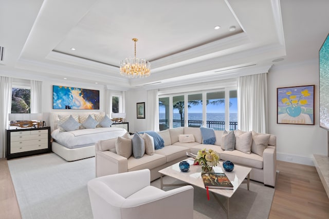 living room with a water view, a notable chandelier, a raised ceiling, and light hardwood / wood-style flooring