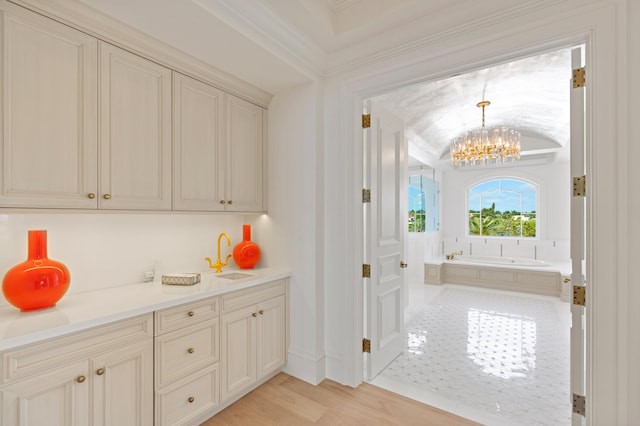 interior space featuring ornamental molding, sink, vaulted ceiling, a notable chandelier, and light wood-type flooring