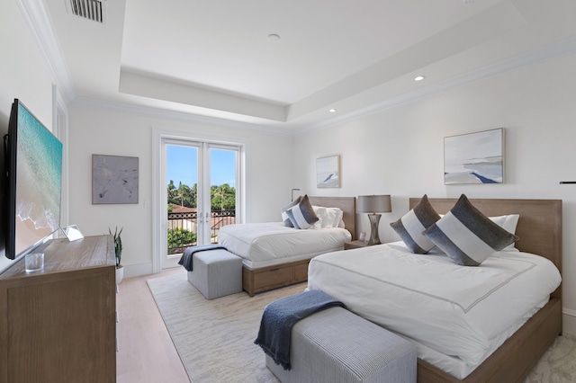 bedroom with light wood-type flooring, french doors, access to exterior, and a tray ceiling