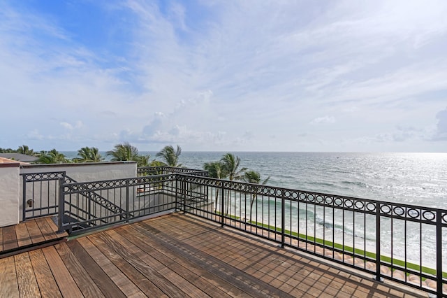 wooden terrace featuring a water view and a beach view