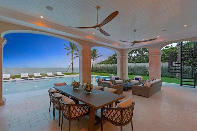 patio terrace at dusk featuring outdoor lounge area, a water view, and ceiling fan