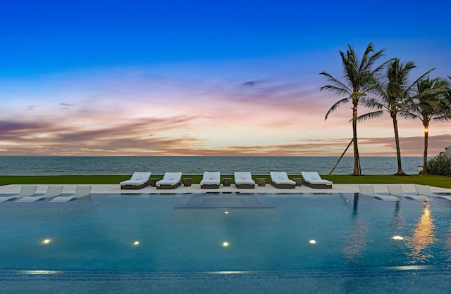 pool at dusk featuring a water view