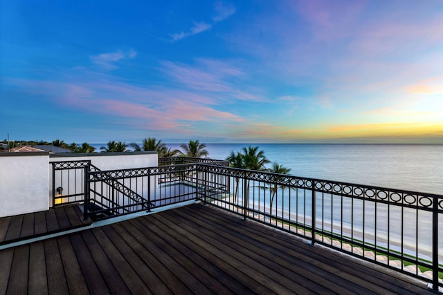 deck at dusk featuring a water view