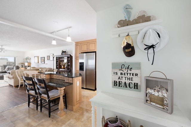 kitchen with pendant lighting, a textured ceiling, light hardwood / wood-style flooring, stainless steel fridge with ice dispenser, and a kitchen breakfast bar