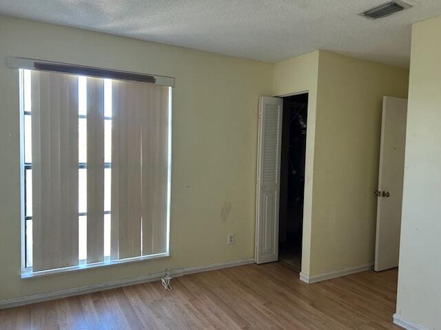 empty room featuring a textured ceiling and light hardwood / wood-style floors