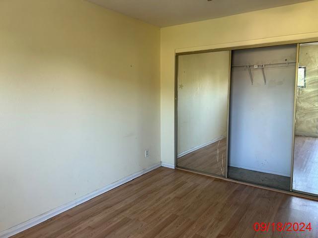 unfurnished bedroom featuring dark hardwood / wood-style flooring and a closet