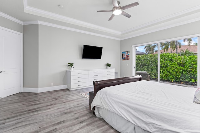 bedroom with ceiling fan, a raised ceiling, crown molding, and light hardwood / wood-style flooring