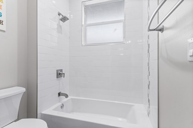 bathroom featuring tiled shower / bath combo and toilet