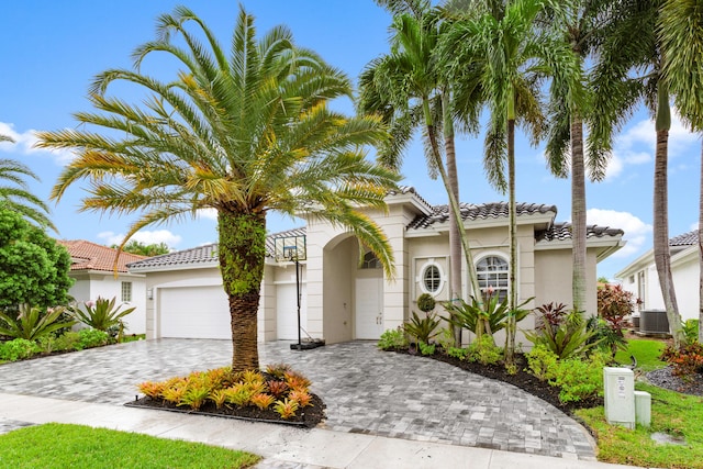 mediterranean / spanish home with central air condition unit and a garage