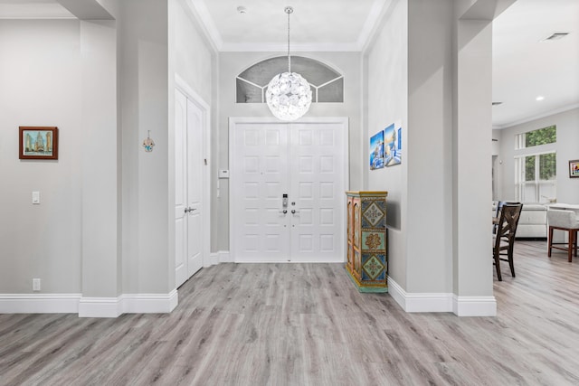 entrance foyer featuring light hardwood / wood-style flooring, an inviting chandelier, and ornamental molding