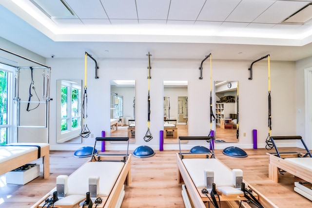 gym featuring hardwood / wood-style flooring and a raised ceiling