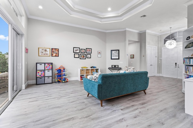 living room with a notable chandelier, light hardwood / wood-style floors, and crown molding