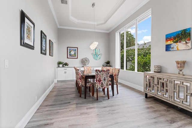 dining area with hardwood / wood-style flooring, a raised ceiling, and ornamental molding