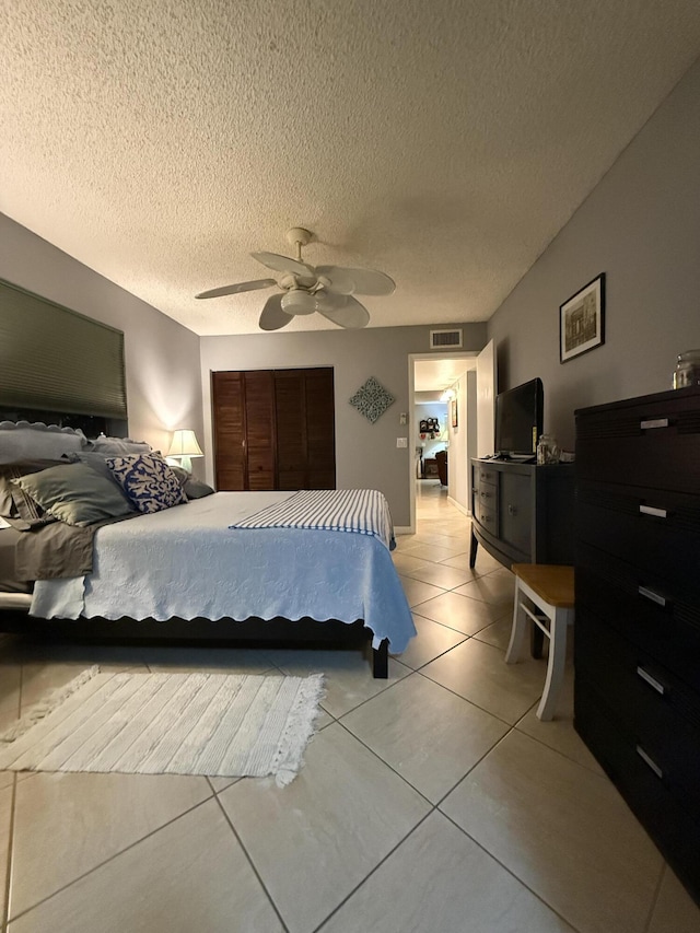 bedroom featuring light tile patterned floors, a textured ceiling, and ceiling fan