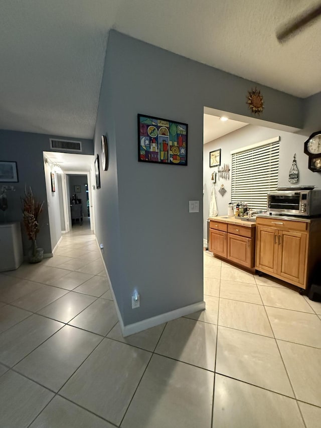 hall with light tile patterned floors and a textured ceiling