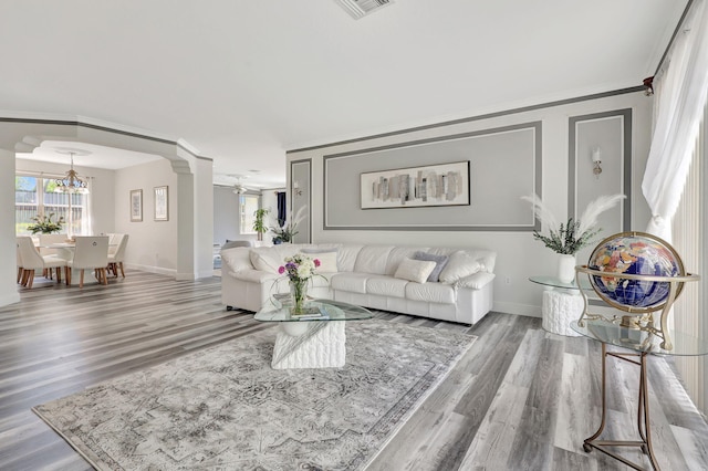 living room with crown molding, hardwood / wood-style flooring, a chandelier, and decorative columns